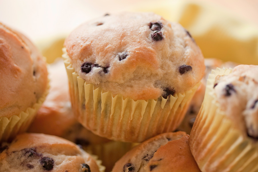 This is a Brian Charles Steel photograph of blueberry muffins shot with a macro lens.  The lighting is soft and the depth of field is shallow.  The muffins fill the frame but the one in the top center is the one in focus. 